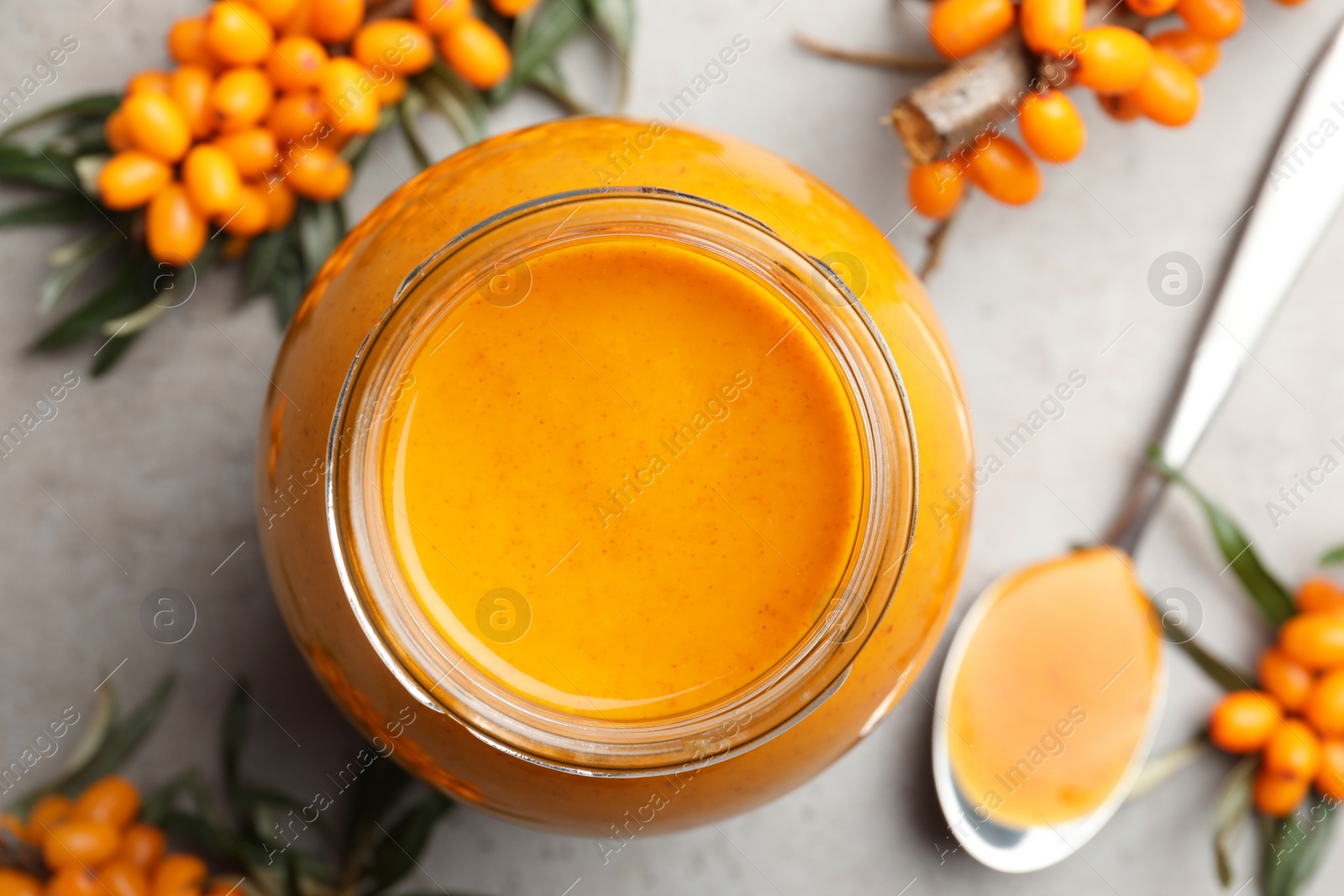 Delicious sea buckthorn jam and fresh berries on grey table, flat lay Photo of Delicious sea buckthorn jam and fresh berries on grey table, flat lay