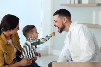 Mother and son visiting pediatrician in hospital. Doctor playing with little boy Photo of Mother and son visiting pediatrician in hospital. Doctor playing with little boy