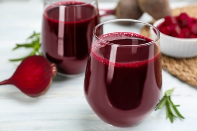 Fresh beet juice and raw vegetable on white table, closeup Photo of Fresh beet juice and raw vegetable on white table, closeup
