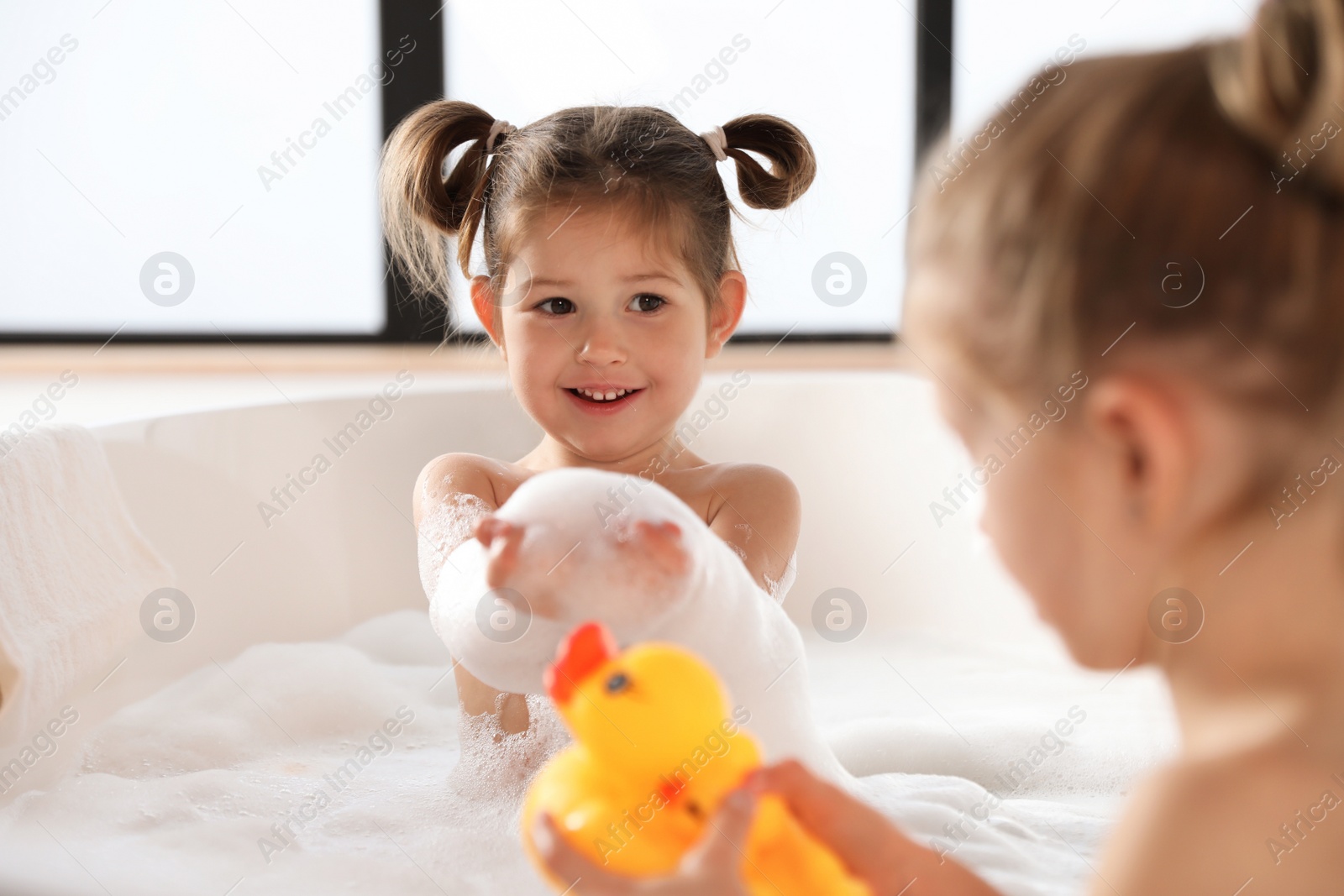 Photo of Cute little sisters taking bubble bath together
