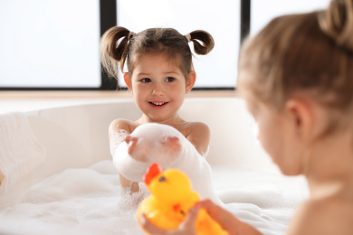 Cute little sisters taking bubble bath together Photo of Cute little sisters taking bubble bath together