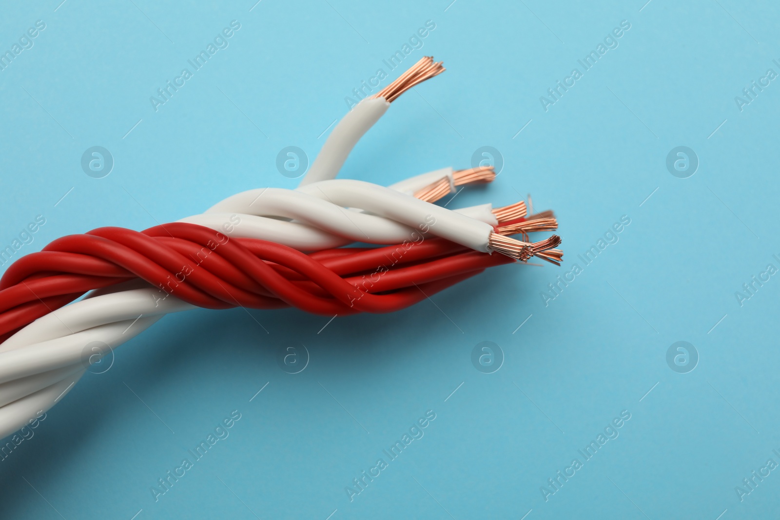 Many twisted electrical wires on light blue background, closeup Photo of Many twisted electrical wires on light blue background, closeup
