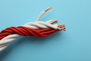 Many twisted electrical wires on light blue background, closeup Photo of Many twisted electrical wires on light blue background, closeup