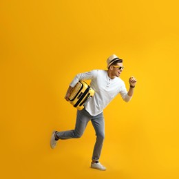 Photo of Male tourist with suitcase running on yellow background