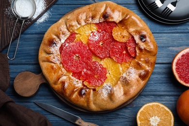 Delicious galette with citrus fruits served on blue wooden table, flat lay Photo of Delicious galette with citrus fruits served on blue wooden table, flat lay