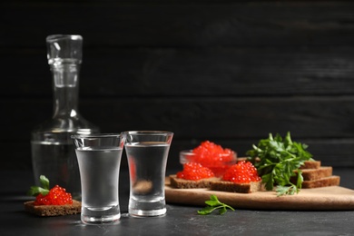 Cold Russian vodka and sandwiches with red caviar on black table Photo of Cold Russian vodka and sandwiches with red caviar on black table