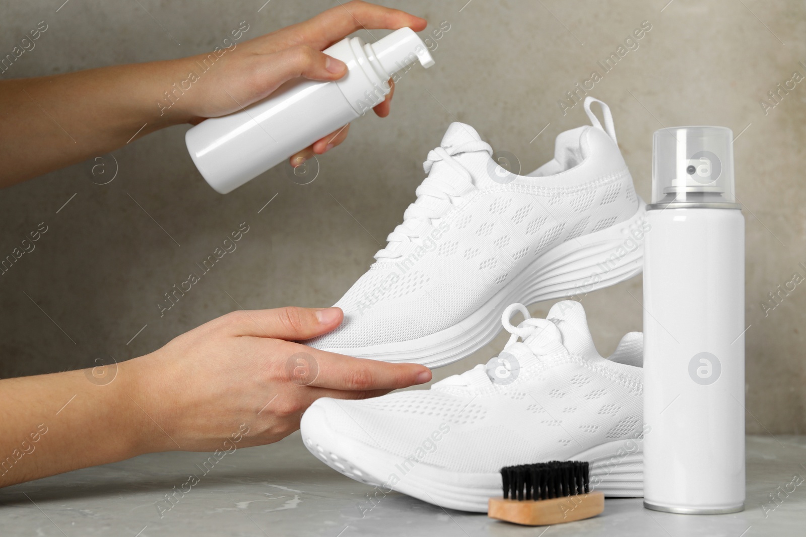 Woman cleaning stylish footwear on grey marble background, closeup. Shoe care accessories Photo of Woman cleaning stylish footwear on grey marble background, closeup. Shoe care accessories