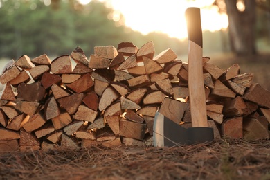Stack of cut firewood and axe in forest, closeup Photo of Stack of cut firewood and axe in forest, closeup