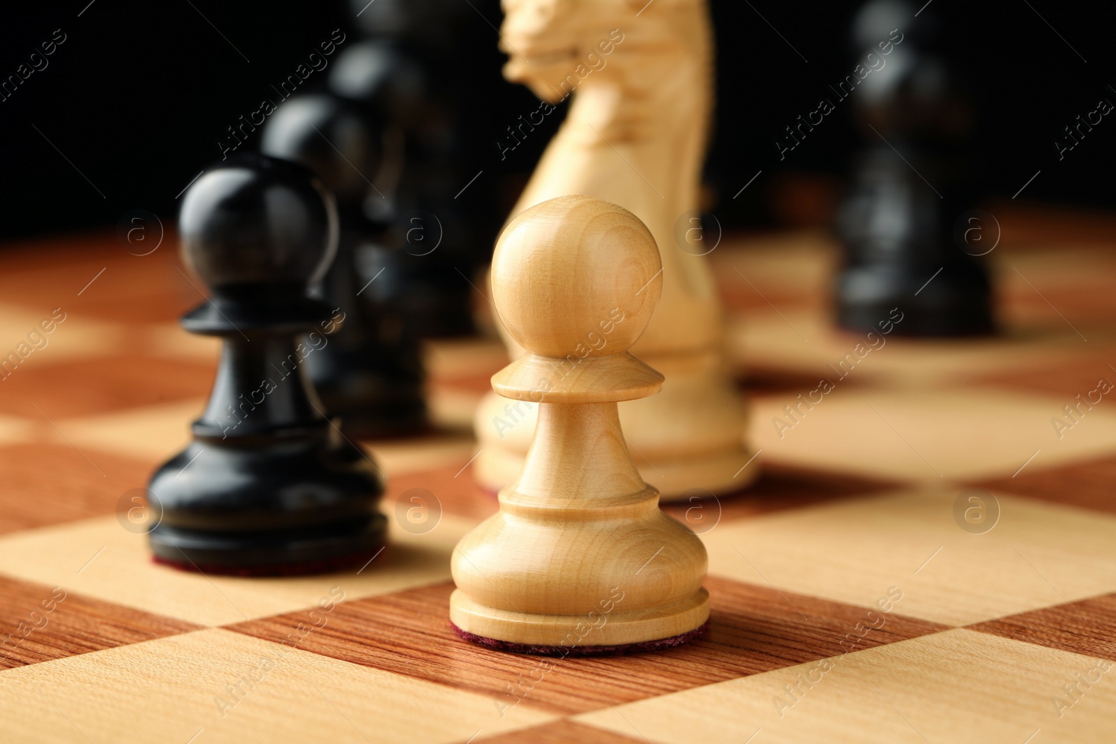 Chessboard with game pieces on black background, closeup Photo of Chessboard with game pieces on black background, closeup