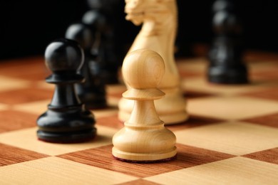 Chessboard with game pieces on black background, closeup Photo of Chessboard with game pieces on black background, closeup