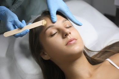 Young woman undergoing hair removal procedure on face with sugaring paste in salon Photo of Young woman undergoing hair removal procedure on face with sugaring paste in salon