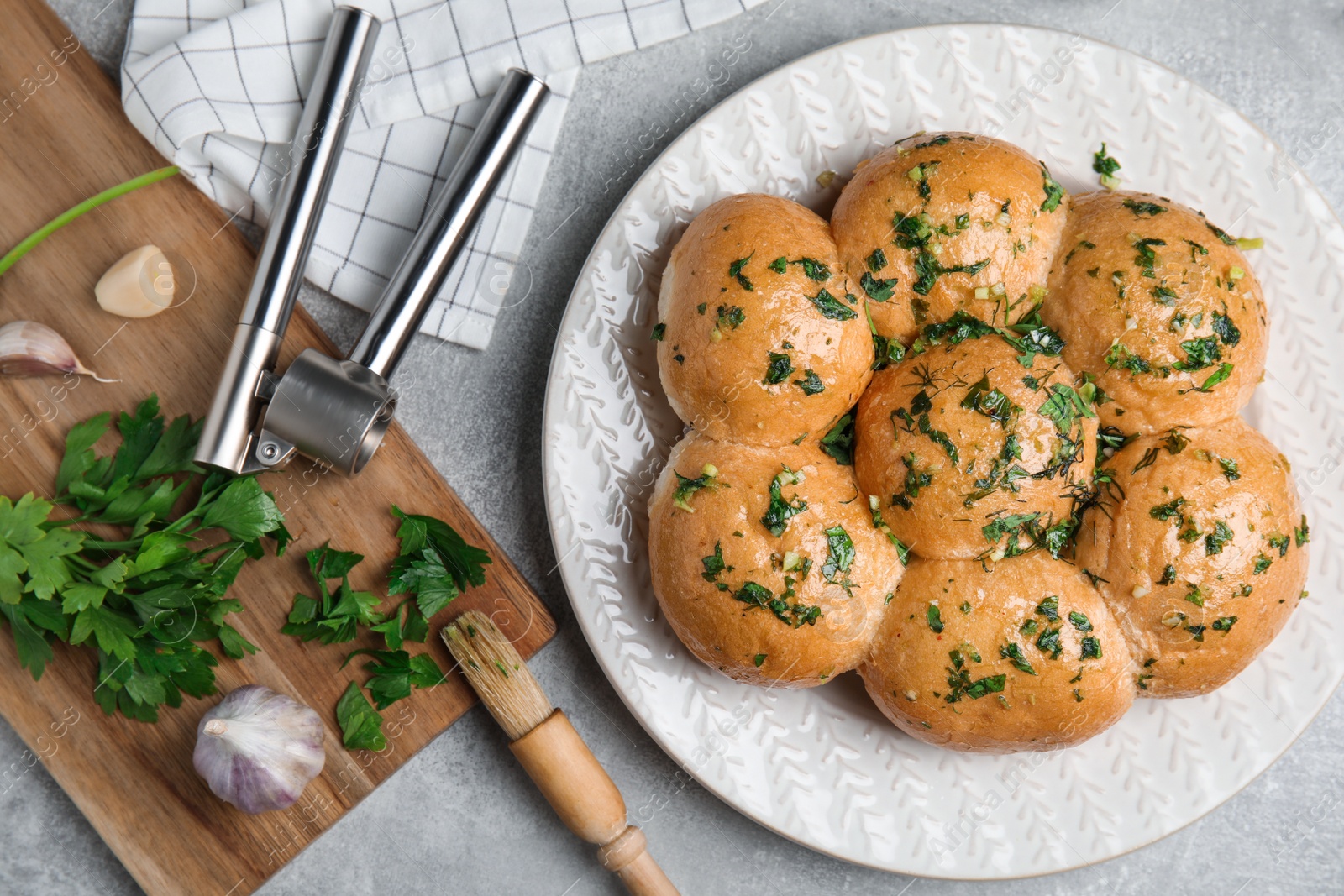 Photo of Traditional pampushka buns with garlic and herbs on grey table, flat lay