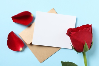 Blank greeting card, envelope and rose on light blue background, flat lay. Valentine's day celebration Photo of Blank greeting card, envelope and rose on light blue background, flat lay. Valentine's day celebration