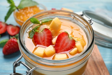 Delicious panna cotta with mango coulis and fresh fruit pieces on light blue table, closeup Photo of Delicious panna cotta with mango coulis and fresh fruit pieces on light blue table, closeup