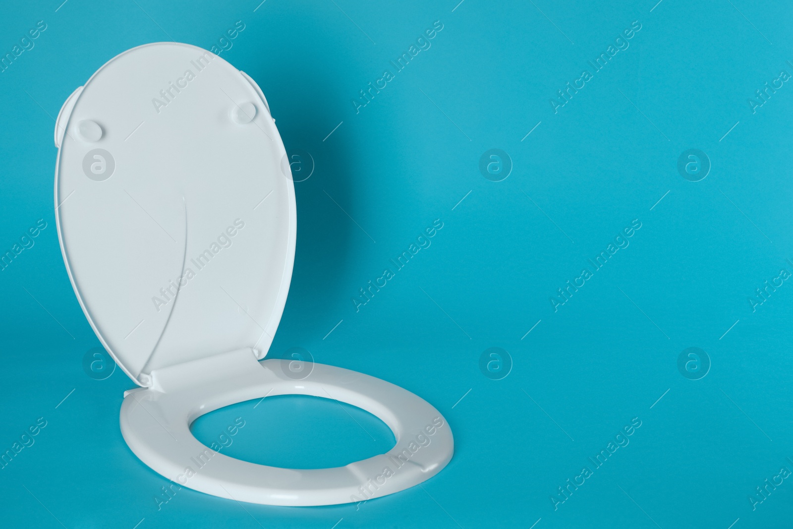 New plastic toilet seat on light blue background, space for text Photo of New plastic toilet seat on light blue background, space for text