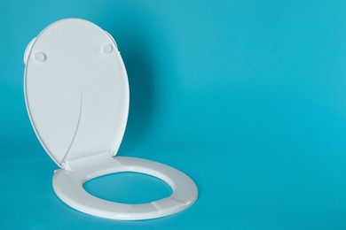 New plastic toilet seat on light blue background, space for text Photo of New plastic toilet seat on light blue background, space for text