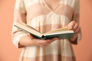 Young woman with book on coral background, closeup Photo of Young woman with book on coral background, closeup