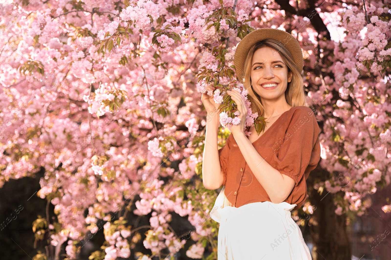 Young woman wearing stylish outfit near blossoming sakura in park. Fashionable spring look Photo of Young woman wearing stylish outfit near blossoming sakura in park. Fashionable spring look