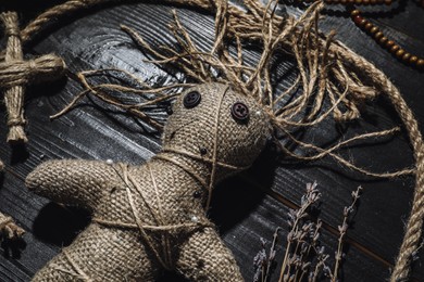 Female voodoo doll with pins surrounded by ceremonial items on black wooden background, closeup Photo of Female voodoo doll with pins surrounded by ceremonial items on black wooden background, closeup