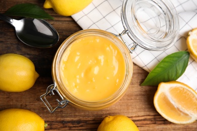 Photo of Delicious lemon curd and fresh fruits on wooden table, flat lay