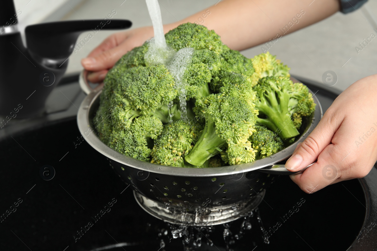 Woman washing fresh green broccoli in kitchen sink, closeup Photo of Woman washing fresh green broccoli in kitchen sink, closeup