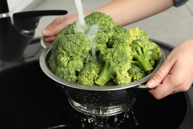 Woman washing fresh green broccoli in kitchen sink, closeup Photo of Woman washing fresh green broccoli in kitchen sink, closeup