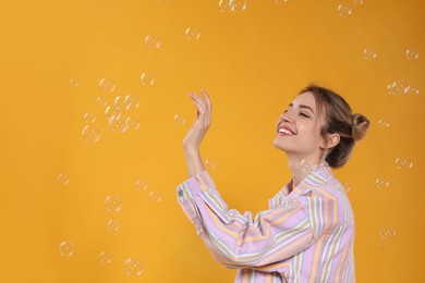 Young woman playing with soap bubbles on yellow background, space for text Photo of Young woman playing with soap bubbles on yellow background, space for text