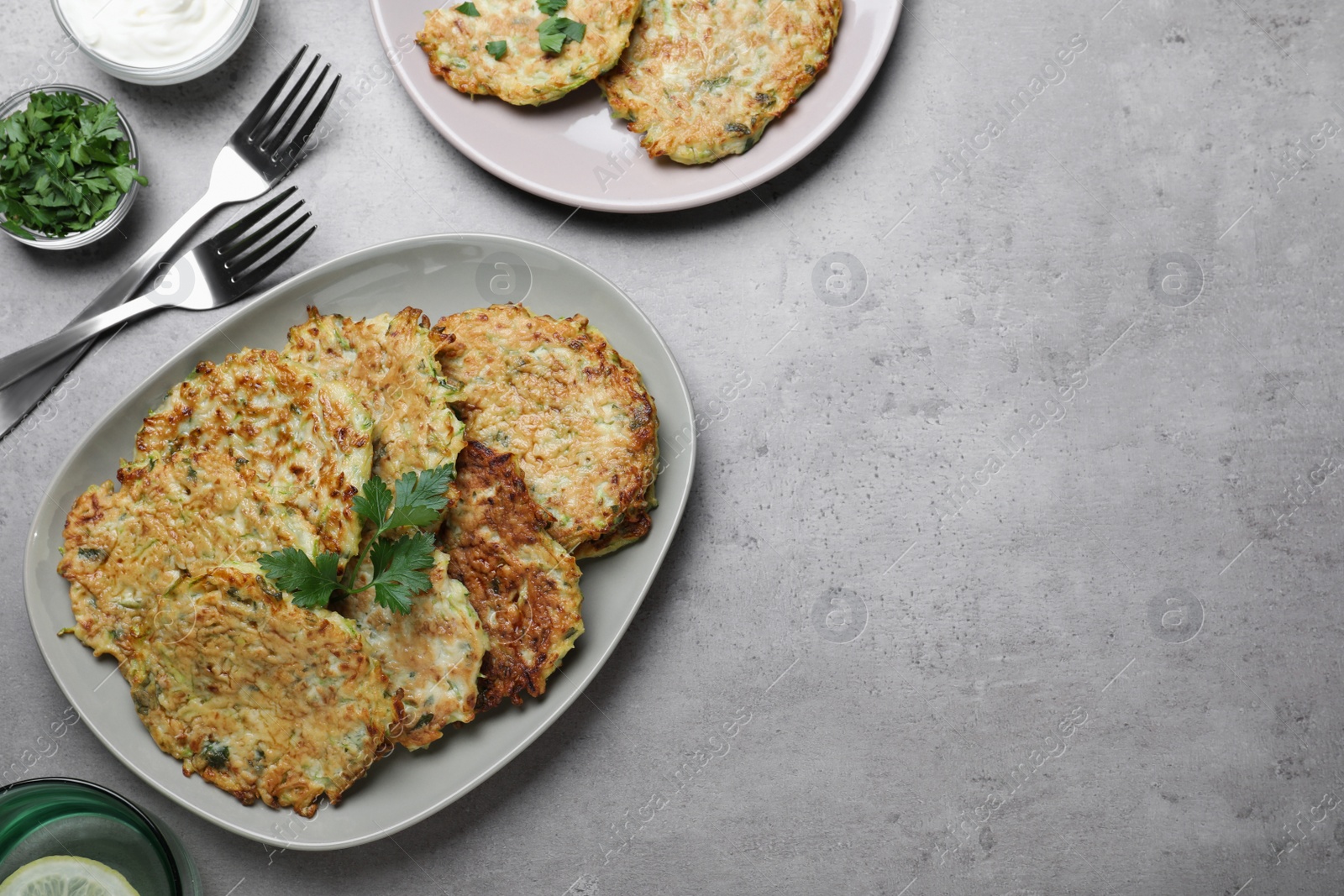 Delicious zucchini fritters served on grey table, flat lay. Space for text Photo of Delicious zucchini fritters served on grey table, flat lay. Space for text