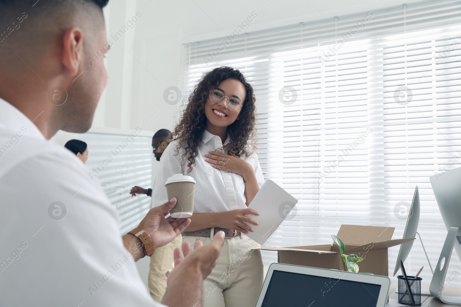 Employee offering cup of coffee to new coworker in office Photo of Employee offering cup of coffee to new coworker in office