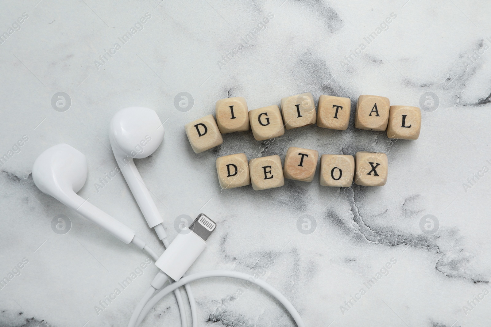 Cubes with phrase DIGITAL DETOX and earphones on white marble table, flat lay Photo of Cubes with phrase DIGITAL DETOX and earphones on white marble table, flat lay