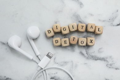 Cubes with phrase DIGITAL DETOX and earphones on white marble table, flat lay Photo of Cubes with phrase DIGITAL DETOX and earphones on white marble table, flat lay