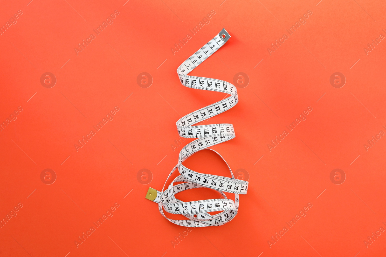 White measuring tape on orange background, top view Photo of White measuring tape on orange background, top view