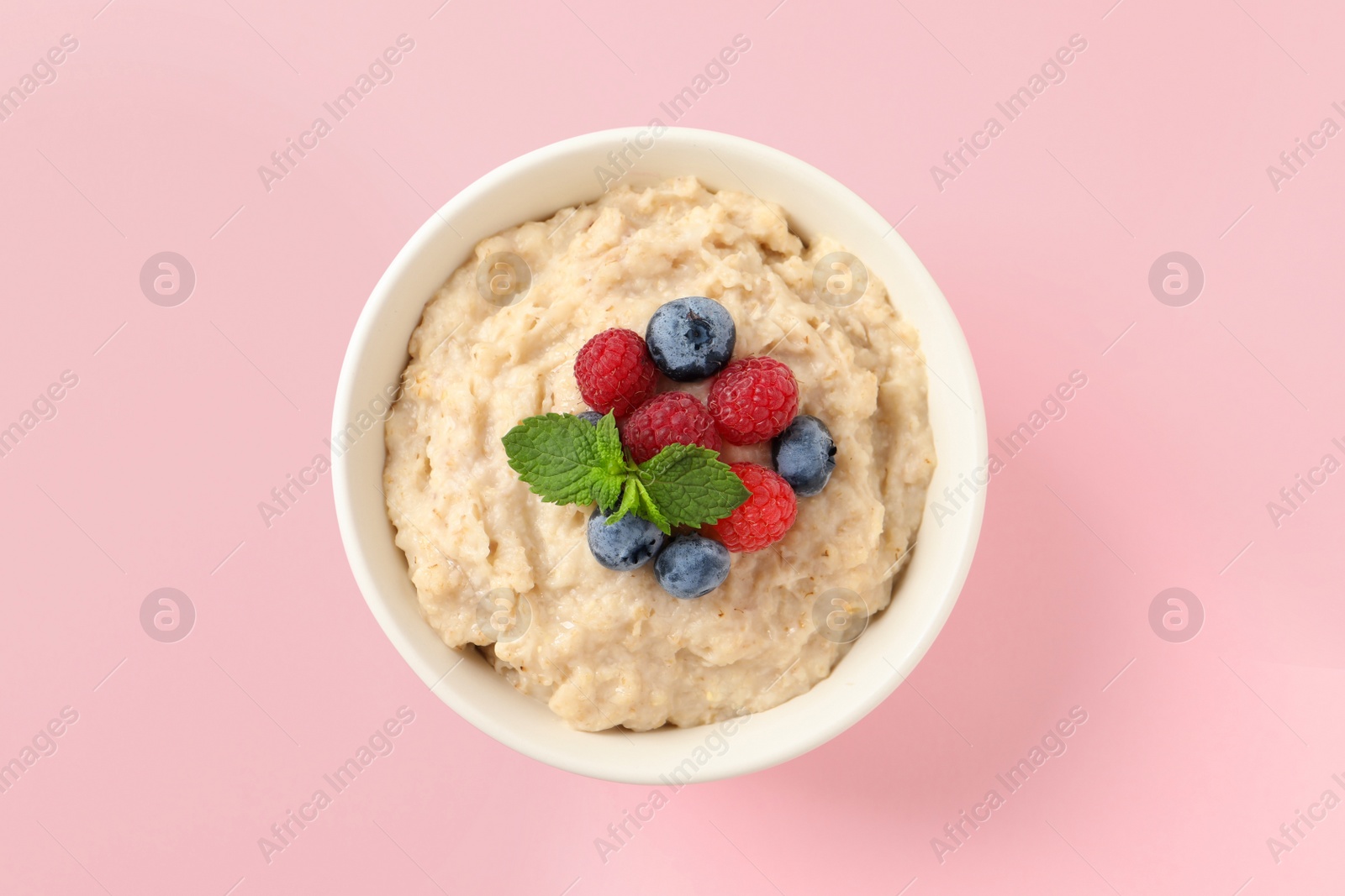 Tasty oatmeal porridge with raspberries and blueberries in bowl on pink background, top view Photo of Tasty oatmeal porridge with raspberries and blueberries in bowl on pink background, top view