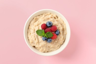 Tasty oatmeal porridge with raspberries and blueberries in bowl on pink background, top view Photo of Tasty oatmeal porridge with raspberries and blueberries in bowl on pink background, top view
