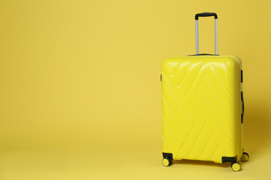 Photo of Stylish suitcase on yellow background. Space for text