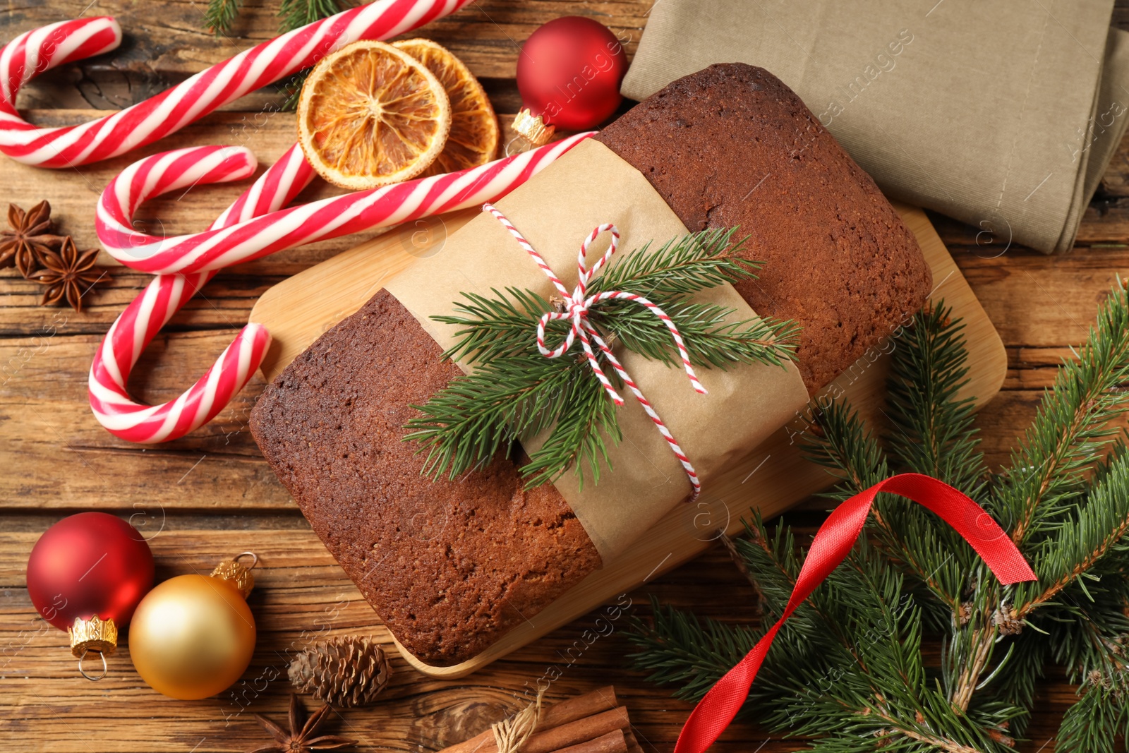 Photo of Delicious gingerbread cake, candy canes and Christmas decor on wooden table, flat lay