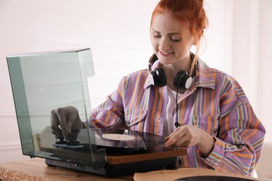 Beautiful young woman using turntable at home Photo of Beautiful young woman using turntable at home