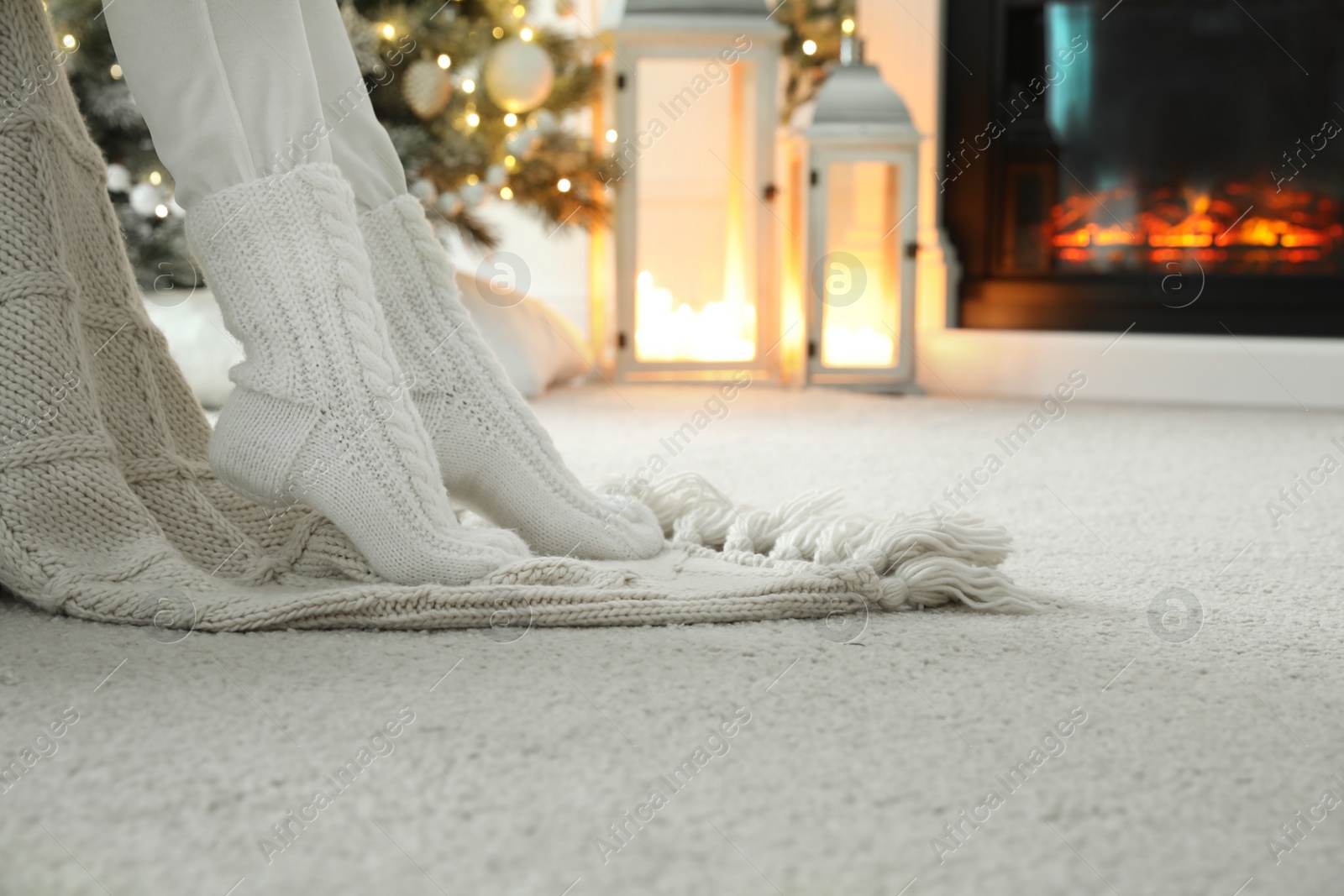 Woman in knitted socks resting near fireplace at home, closeup Photo of Woman in knitted socks resting near fireplace at home, closeup