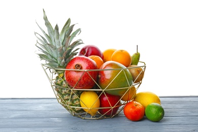 Metal basket with fresh tropical fruits on table Photo of Metal basket with fresh tropical fruits on table
