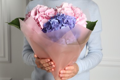 Photo of Woman with bouquet of beautiful hortensia flowers near white wall, closeup