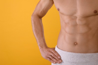 Shirtless man with slim body and towel wrapped around his hips on yellow background, closeup Photo of Shirtless man with slim body and towel wrapped around his hips on yellow background, closeup