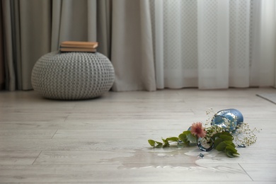 Broken blue glass vase and bouquet on floor in room. Space for text Photo of Broken blue glass vase and bouquet on floor in room. Space for text