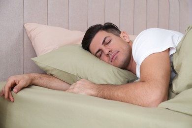 Man sleeping in comfortable bed with green linens Photo of Man sleeping in comfortable bed with green linens