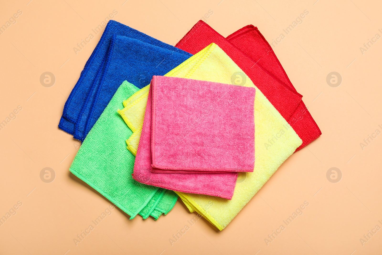 Many colorful microfiber cloths on beige background, flat lay Photo of Many colorful microfiber cloths on beige background, flat lay