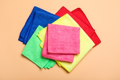 Many colorful microfiber cloths on beige background, flat lay Photo of Many colorful microfiber cloths on beige background, flat lay