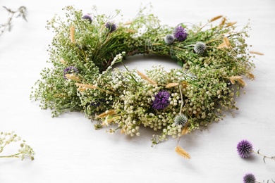 Beautiful wreath made of wildflowers on white table Photo of Beautiful wreath made of wildflowers on white table