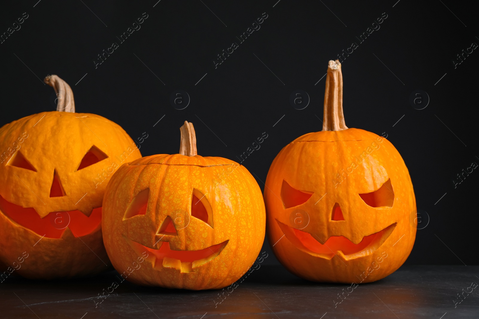 Pumpkins with scary faces on black background. Halloween traditional decor Photo of Pumpkins with scary faces on black background. Halloween traditional decor