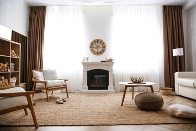 Elegant artificial fireplace and armchairs in room. Interior design Photo of Elegant artificial fireplace and armchairs in room. Interior design