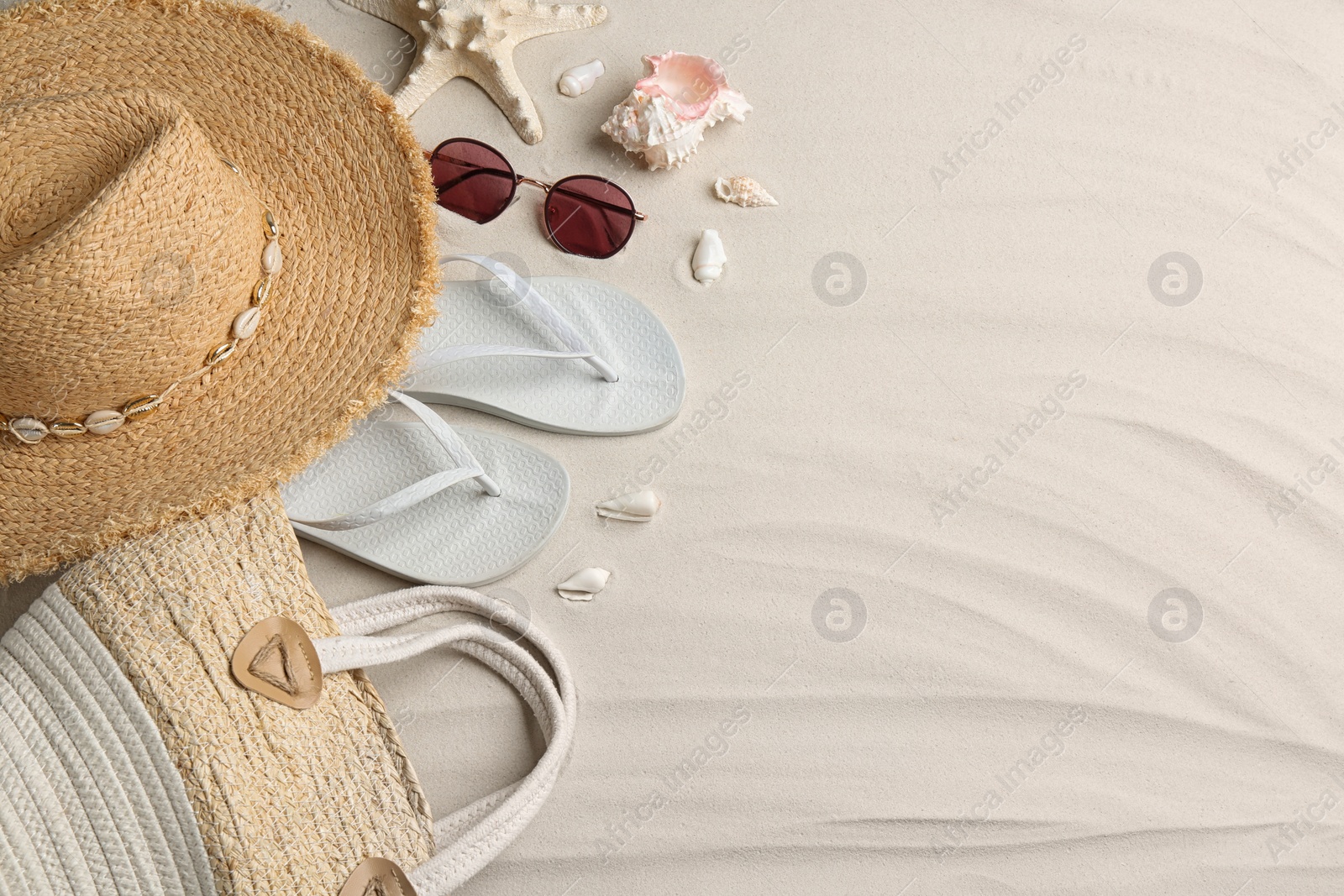 Photo of Different beach accessories on sand, flat lay. Space for text