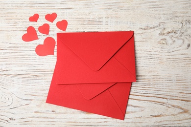Red envelopes and paper hearts on white wooden table, flat lay. Love letters Photo of Red envelopes and paper hearts on white wooden table, flat lay. Love letters